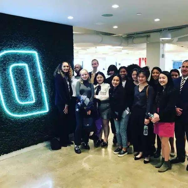 Group of students next to a giant, neon "D"