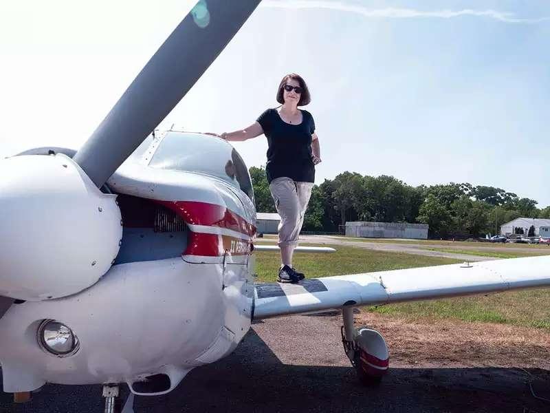 Beverly Weintraub stands on the wing of her small plane