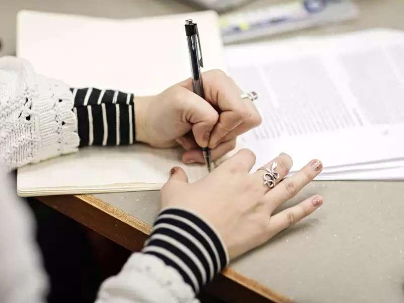 Close-up of a person's hands writing on paper